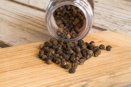 Whole black pepper from a bottleの写真素材