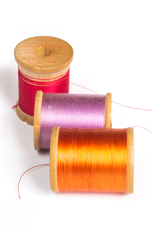 Three spools of colorful thread on white background