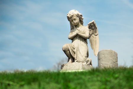 Praying Angel statue in graveyardの写真素材