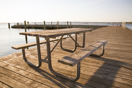 Wooden picnic benches and table on wood pier on waterの写真素材