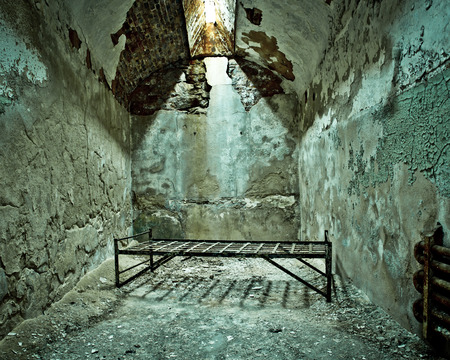 Cot in empty crumbling prison cell at Eastern State Penitentiaryの写真素材