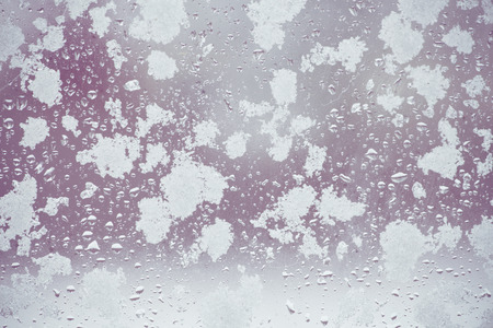 toned winter window with snow and water dropletsの写真素材