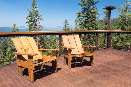 Two wood chairs on outdoor sunny deck with mountains in the backgroundの写真素材