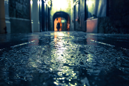 Focus on wet ground along dark medieval alley on a rainy night, Butter Slip, Kilkenny Ireland.の写真素材