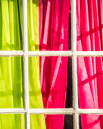 Colorful pink and green curtains seen from exterior window with French paneの写真素材