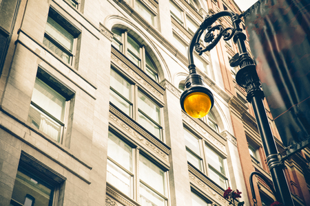 Vintage style illuminated streetlamp with New York City apartment buildings in the background.の写真素材