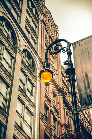 Vintage style illuminated streetlamp with New York City apartment buildings in the background.の写真素材