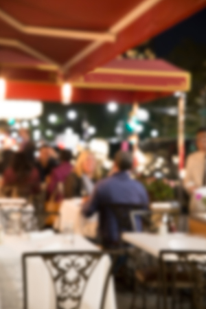 Defocused blur of outdoor restaurant scene with non recognizable diners at nightの写真素材