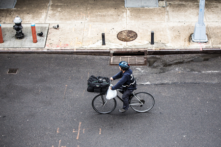 NEW YORK CITY - MARCH 29, 2018: New York City, Manhattan street scene viewed from above with man riding bicycle and pedestrians seen from Chelsea.のeditorial素材
