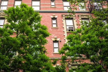 Typical New York City brick apartment building in spring surrounded by green trees.の写真素材