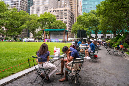 New York City - June 12, 2021:  Scene from historic Bryant Park in midtown Manhattan on a Saturday afternoon with people visiting and event stage in the background.のeditorial素材