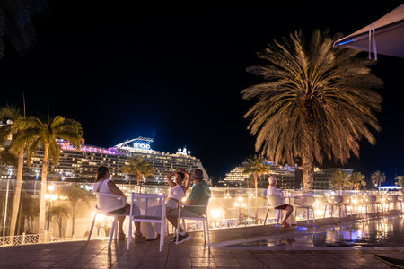 Oranjestad, Aruba - May 21, 2024:  Evening view from the city of Oranjestad Aruba with visitors, palm trees and cruise ship at port.のeditorial素材