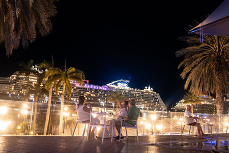 Oranjestad, Aruba - May 21, 2024:  Evening view from the city of Oranjestad Aruba with visitors, palm trees and cruise ship at port.のeditorial素材