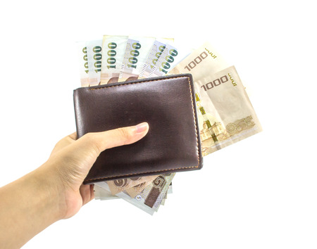 female's hand holding 1000 banknotes in brown leather wallet isolated on white background, Thai...