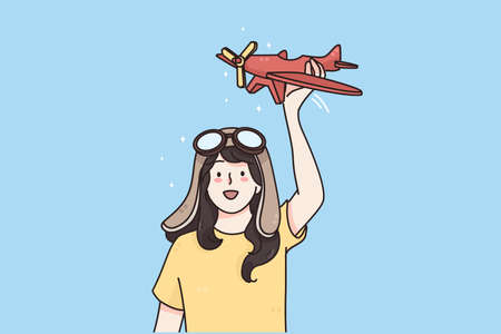 Happy childhood and games concept. Young smiling girl in goggles standing with toy plane in hands and playing imagining her pilot vector illustrationのイラスト素材