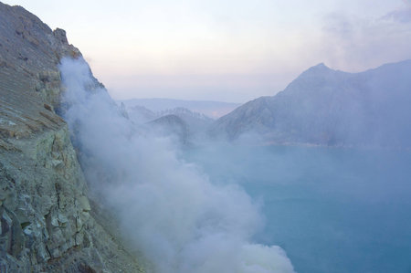 Ijen volcano in East Java contains the world's largest acidic volcanic crater lake, called Kawah Ijen, spewing out sulphur smoke in the morning. Sun is hidden in mist.の写真素材