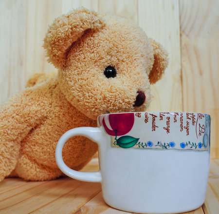 A coffee cup with teddy bear and wooden background. vintage style.の写真素材