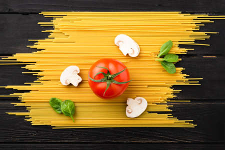 Spaghetti with tomato, mushrooms and spinach on black background. Top view. Healthy eating concept. Preparation of productsの写真素材