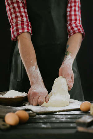 Beautiful and strong men's hands knead the dough from which they will then make bread, pasta or...