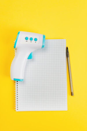 List of medications. Paper notebook with pen and thermometer, top view list of pills on yellow...