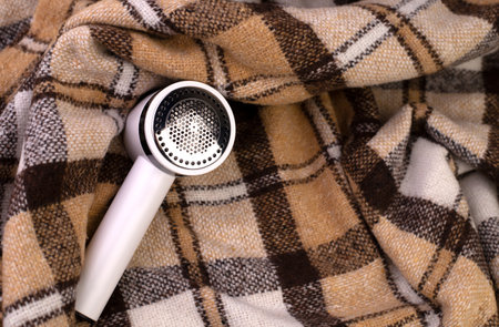 Electric device for removing hair and down on a blanket or brown plaid. Razor for wool. Machine for removing granules. Textile care conceptの写真素材