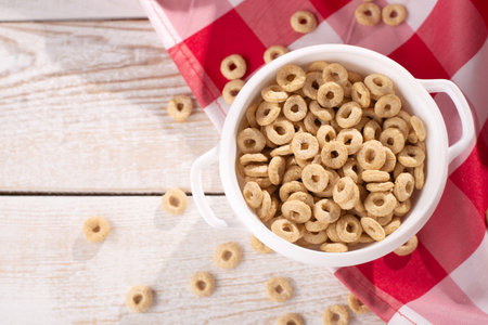 healthy cereal rings on a light wood background with tablecloth red in a plate and scattered on the table with sun rays. morning eat. Healthy children's breakfast. Dry muesliの写真素材