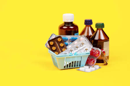 A bunch of pills in a grocery basket on a yellow background. Pharmacies make a profit. Medications for covid. Remedy for colds and flu Tablets, bottlesの写真素材