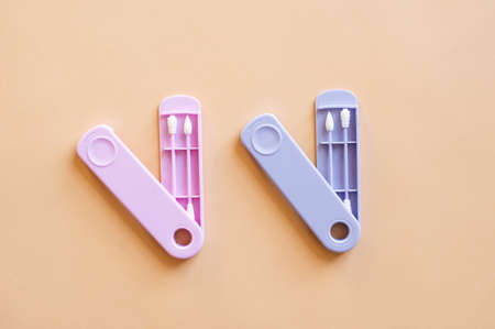 Reusable silicone ear sticks in colored cases with a top view on a beige background. An alternative to disposable cotton swabs. Reduce costs and save money.の写真素材