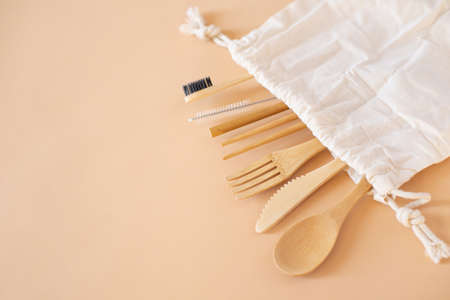 Eco friendly bag and bamboo cutlery set with toothbrush on beige background for green life and zero waste concept. Top viewの写真素材