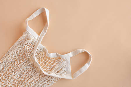 Eco friendly string bag on beige paper background, responsible consumption. Ecological concept. Caring for the environment and the rejection of plastic. Mesh bagの写真素材