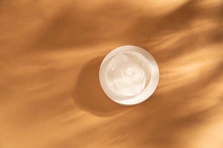 Flat lay with a container of body cream on beige