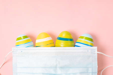 Easter Eggs 2021 with  virus Defense Concept  . Easter eggs under a medical mask on pastel pink....