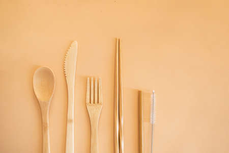 Eco friendly bamboo cutlery set on a beige background top view. Zero waste concept. Spoon, fork,...