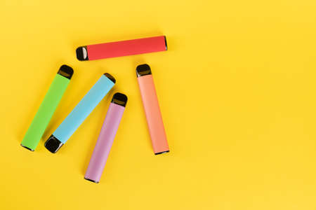 Layout of colorful disposable electronic cigarettes on a yellow background. The concept of modern smoking, vaping and nicotine.の写真素材