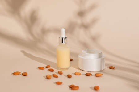 Dropper glass bottle Mock-Up and container with cream. Body treatments and spa on a beige background. Natural beauty products based on almonds. Eco cream, serum, skin care bottleの写真素材