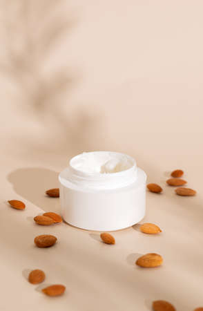 skin care cream with almonds on a beige background with hard shadows. based on natural ingredients.の写真素材