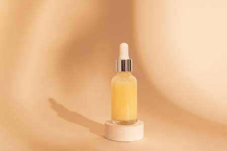 Dropper glass Bottle Mockup. osmetic pipette on beige background with shadows on stone round podium. Essential oilの写真素材
