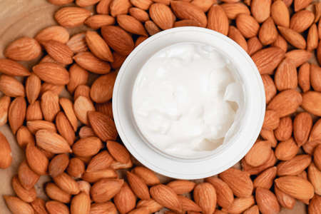 Jar of cosmetic cream and almond on wood background. Concept idea for cosmetic product with natural ingredients. top viewの写真素材