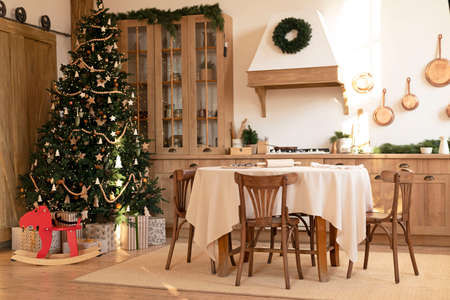 kitchen decorated with pine garlands and Christmas toys. the table and near is worth Christmas tree....