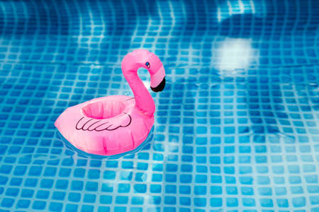 Pink inflatable flamingo in pool water for summer beach background. Minimal summer concept.の写真素材