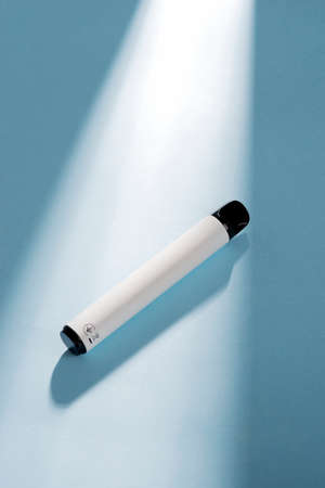 White disposable electronic cigarette on a blue background with hard light. The concept of modern smoking. elf bar.の写真素材