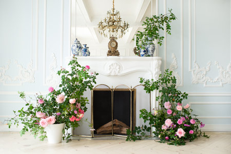 Bright luxury white and blue colored interior living room with flowers in vases. the walls are decorated with rococo. Vase with flowers on the background of a decorative fireplace in the living room.の写真素材