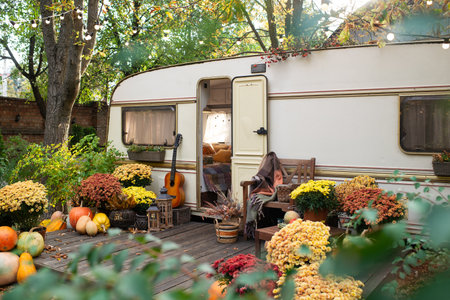 Mobile home van with terrace at sunset in autumn, mobile home, orange fallen leaves. autumn decor,...