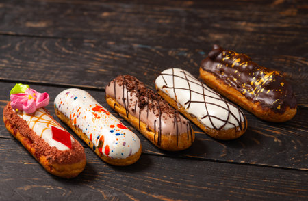 Beautiful delicious French eclairs set with original cream decor on dark wood background. close-up...