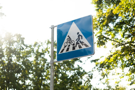 Blue and white Pedestrian and Bicycles Crossing road sign on green lushy sunny background.の写真素材