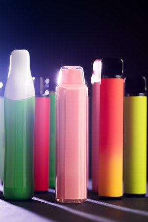A set of colorful disposable electronic cigarettes of different shapes on a black background.の写真素材