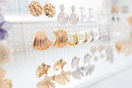 Elegant display of various gold and silver earrings on a transparent holder with a soft-focus background.の写真素材