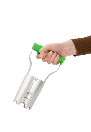 Hand holding a bulb planter tool with a green handle, isolated on white background.の写真素材