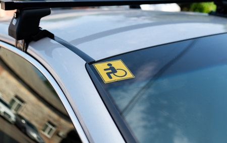Yellow disabled sign sticker on car windshield indicating vehicle accessibility for persons with disabilitiesの写真素材