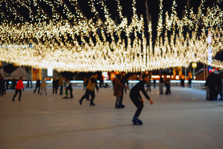 A vibrant outdoor Christmas and winter holiday market featuring an ice rink, festive decorations, colorful buildings, and illuminated snow globesの写真素材